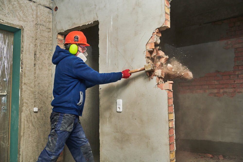 man demolishing wall with sledgehammer
